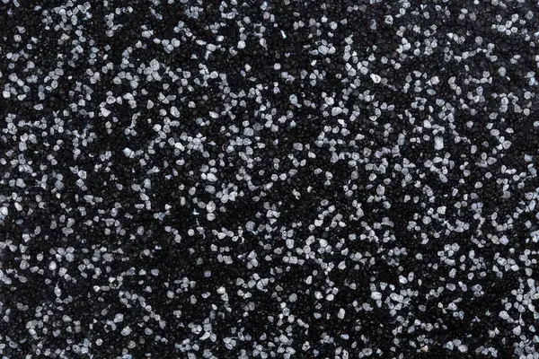 Close-up of coarse white salt crystals scattered over a dark epoxy flooring surface, creating a striking contrast and textured background reminiscent of a stylish Miami garage epoxy floor.