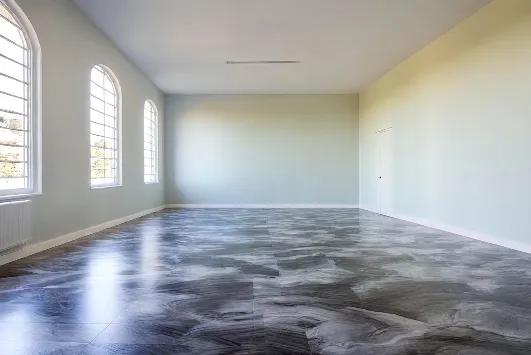 Spacious empty room in Hialeah with large arched windows, light blue walls, and dark epoxy flooring that mimics marble. Sunlight streams in, creating a bright and airy atmosphere.