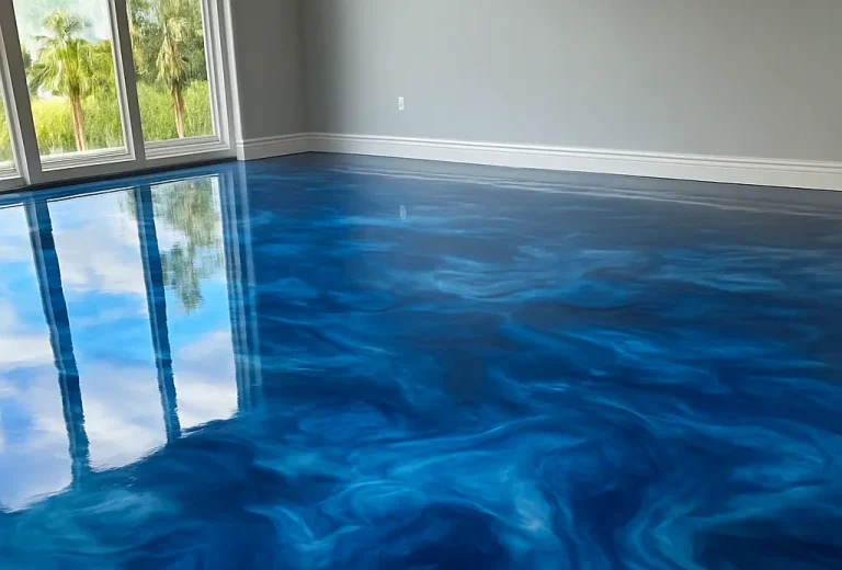 A room with large windows and a glossy, blue epoxy resin floor that resembles swirling ocean water, reflecting the sky and window light—an inspiring example of Epoxy Floor Miami style.